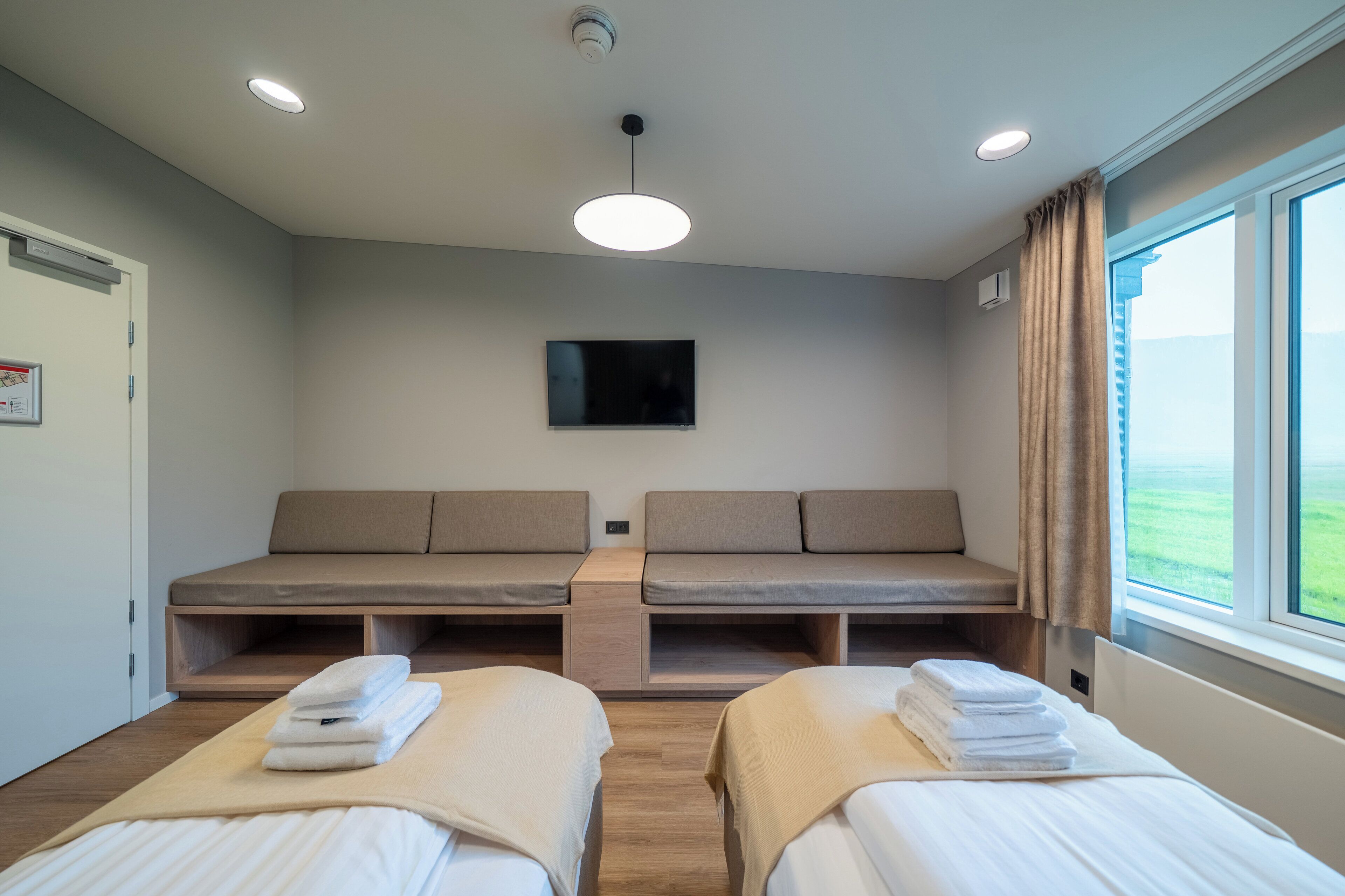 A hotel room with two beds, a television, and a window with a view.