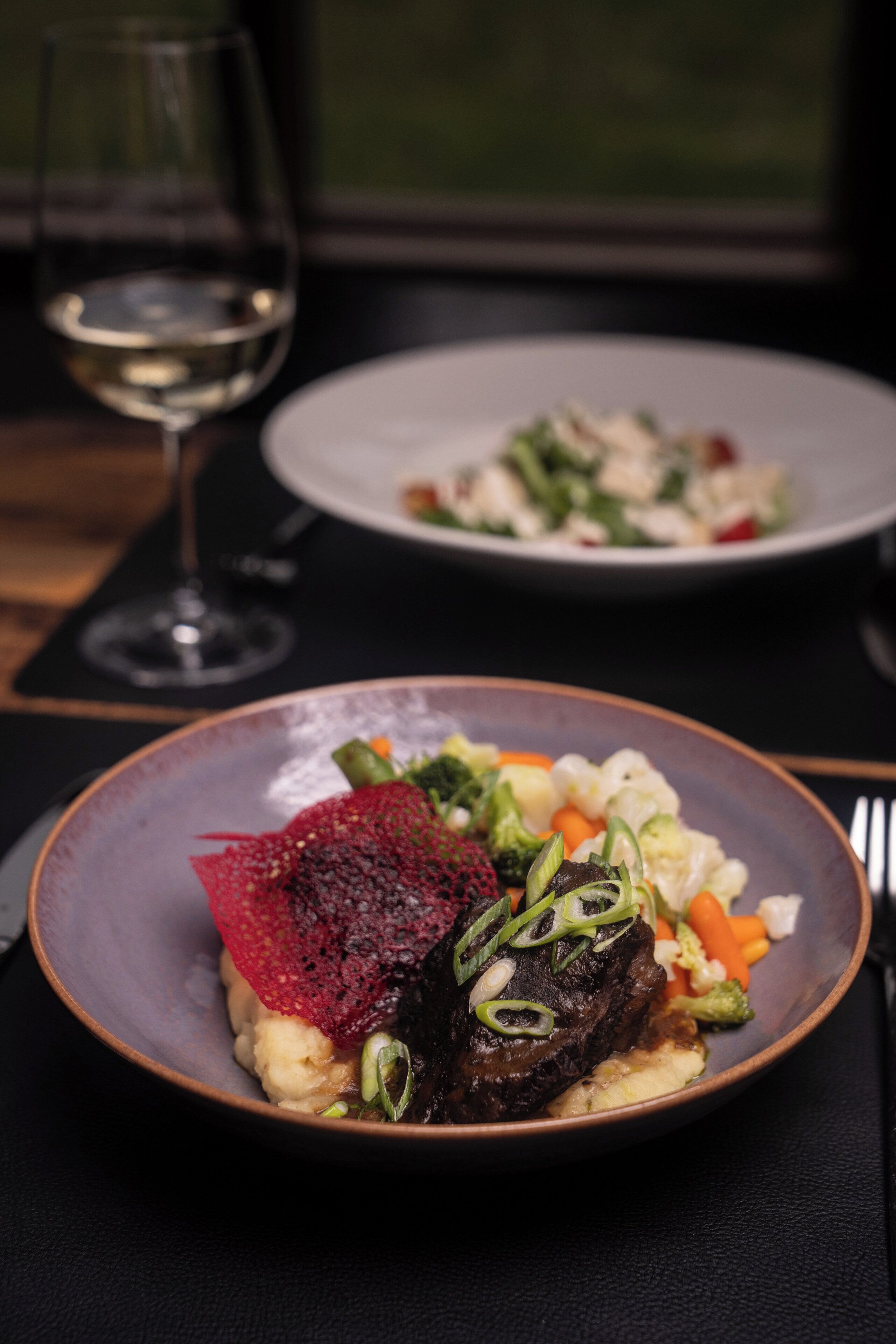 Een eettafel met borden eten, een wijnglas en bestek.