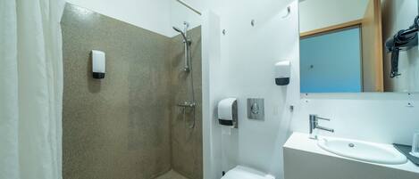 Un baño moderno con ducha, inodoro, lavabo y secamanos.