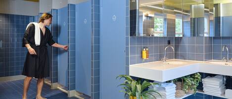 A modern bathroom with blue tiles, a white sink, and a mirror.