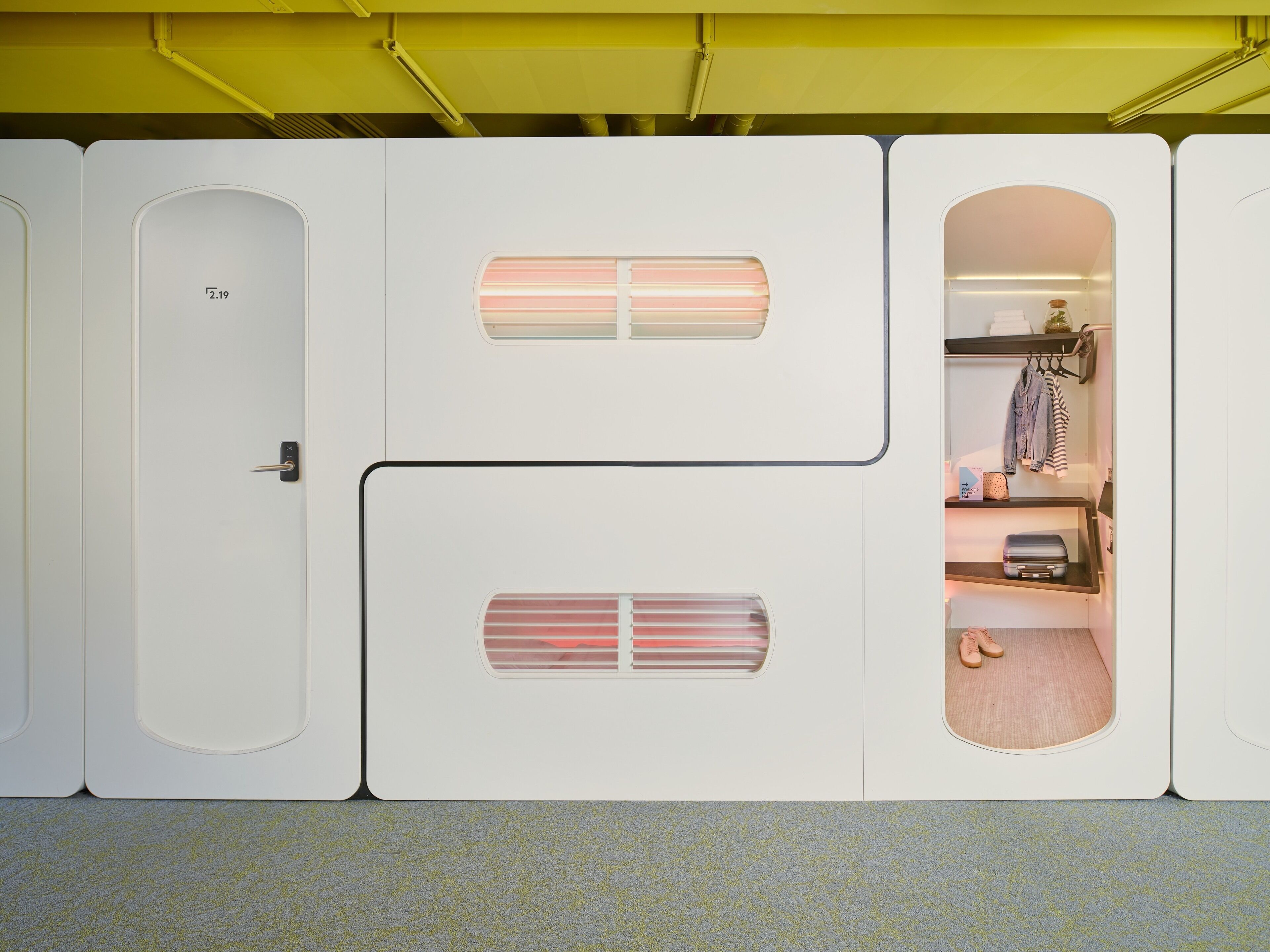 Een compacte, moderne kamer met een inbouwkast, een klein zithoekje en een open kast met kleding.