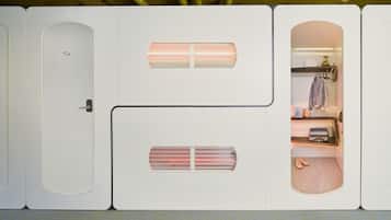 Een compacte, moderne kamer met een inbouwkast, een klein zithoekje en een open kast met kleding.
