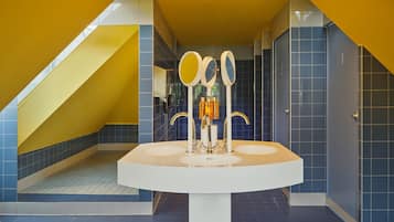 A modern bathroom with a central sink, two mirrors, and a towel rack.