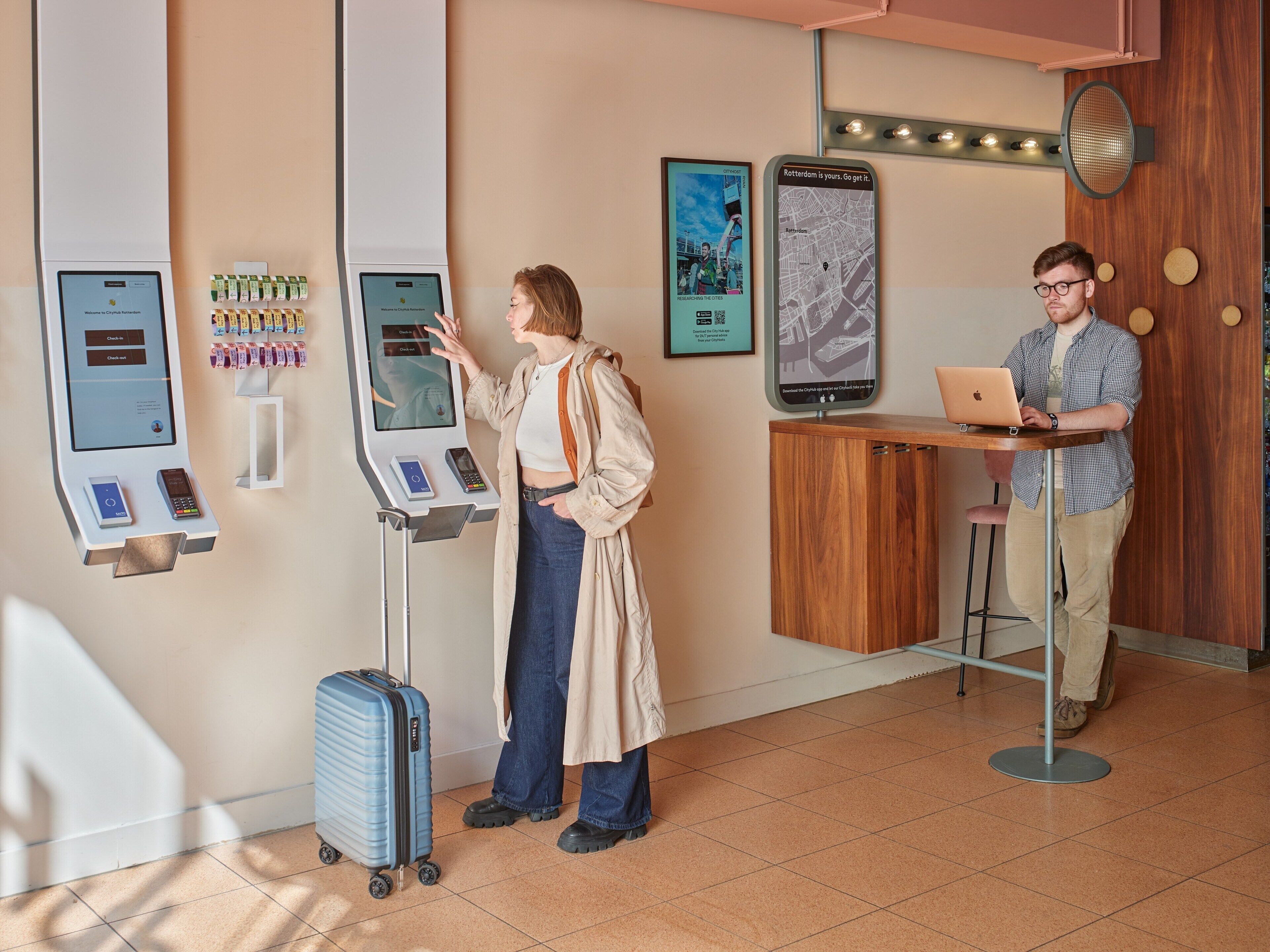 Un quiosco de registro, un mapa digital y una computadora portátil sobre un mostrador en el vestíbulo de un hotel.