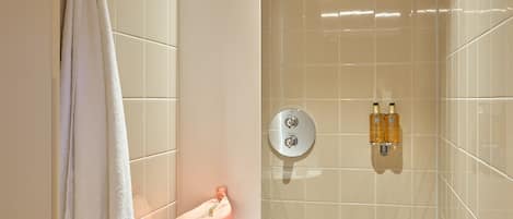 A modern bathroom with a shower, a towel rack, and a shelf with toiletries.