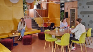 A modern interior with a wooden table, yellow chairs, and a staircase leading to a mezzanine. - CityHub Rotterdam (Rotterdam)