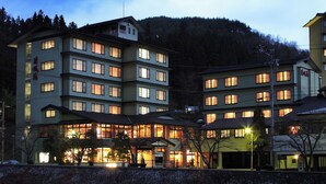 Un hotel de varios pisos con un patio central, rodeado de árboles y un paisaje montañoso.