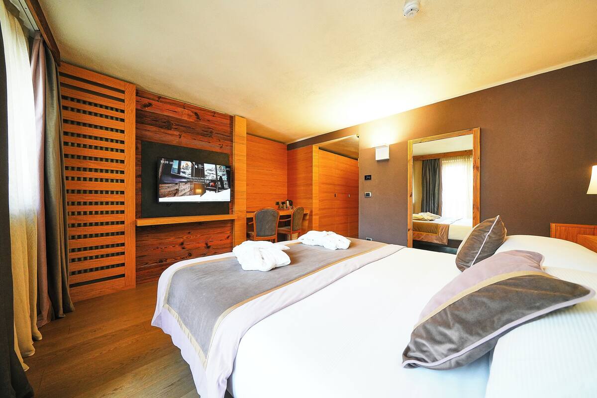 A hotel room with a bed, a TV, a desk, and a mirror.