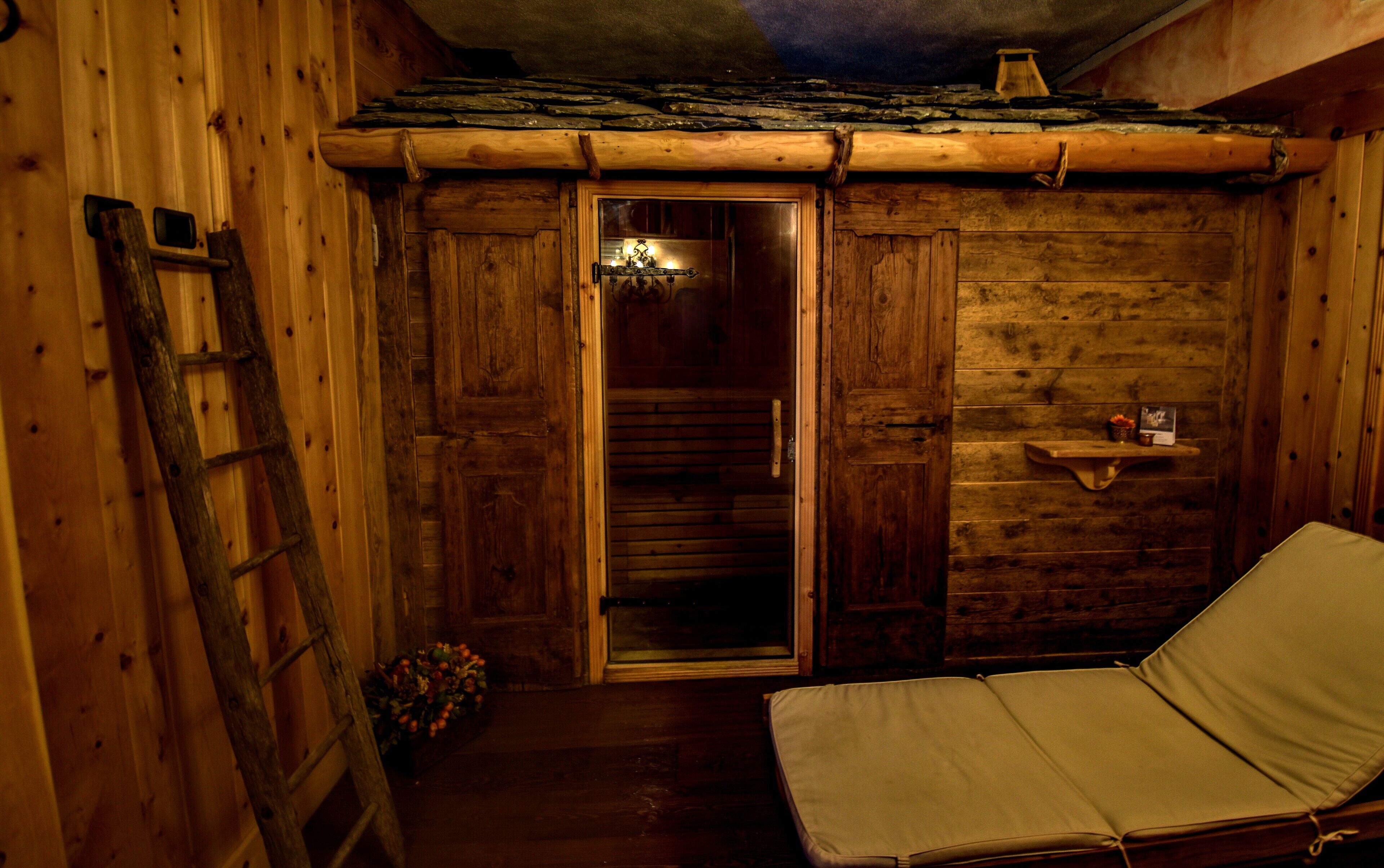 Una cabaña de madera con un baño pequeño, una escalera de madera y una cama individual.