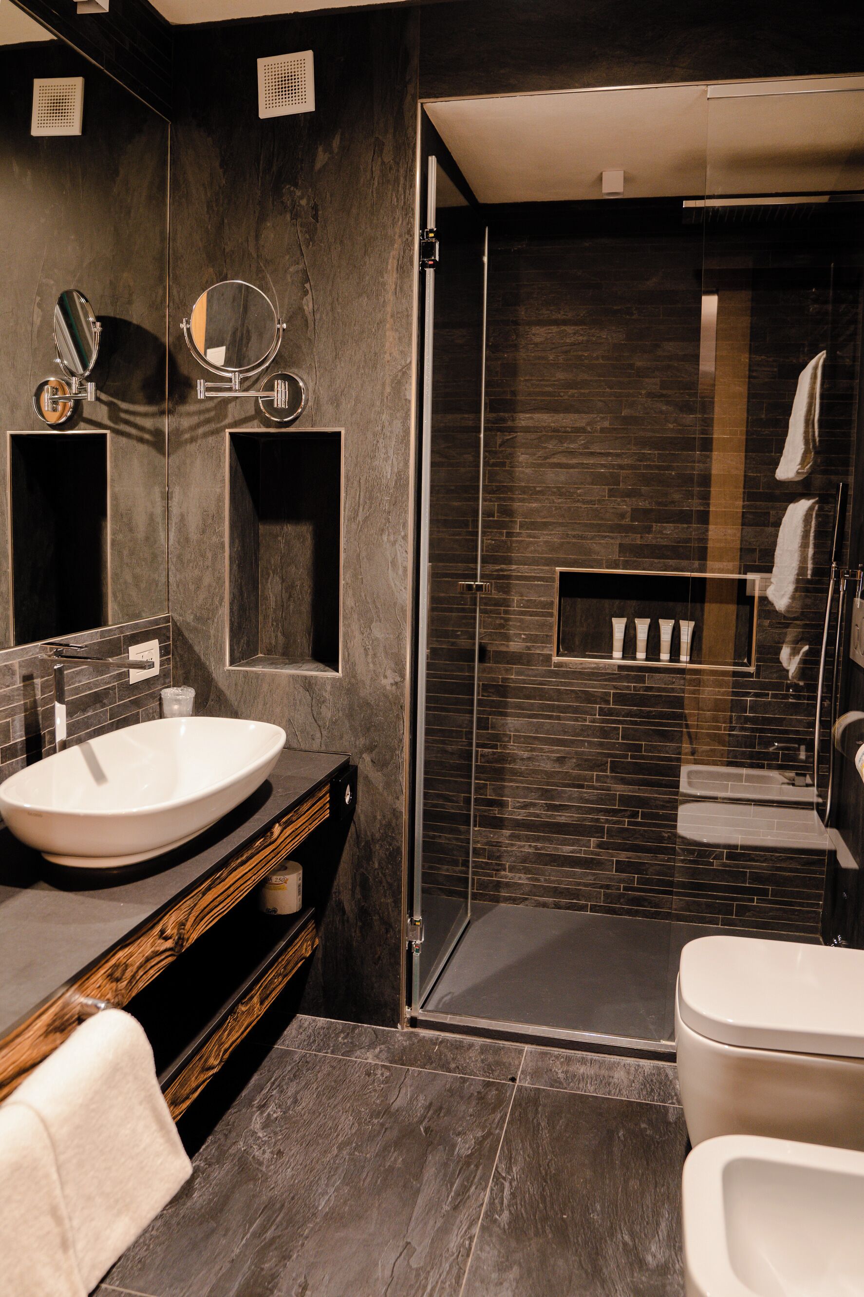 Une salle de bain moderne dotée d’un grand lavabo, d’un miroir et d’une cabine de douche en verre.