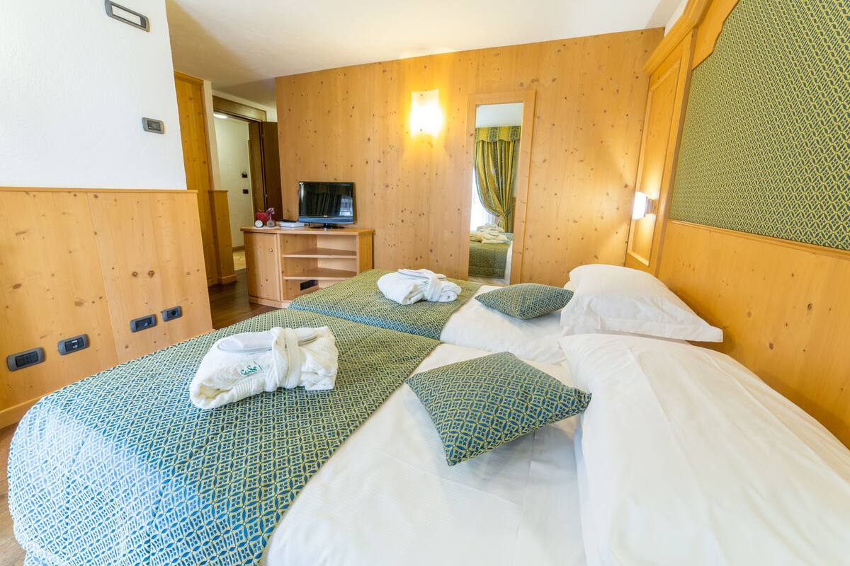 A hotel room with two beds, a TV, and a wooden panel wall.