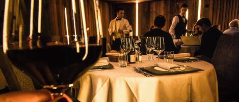 A restaurant with round ceiling lights, a table set for dining, and a person holding a wine glass.