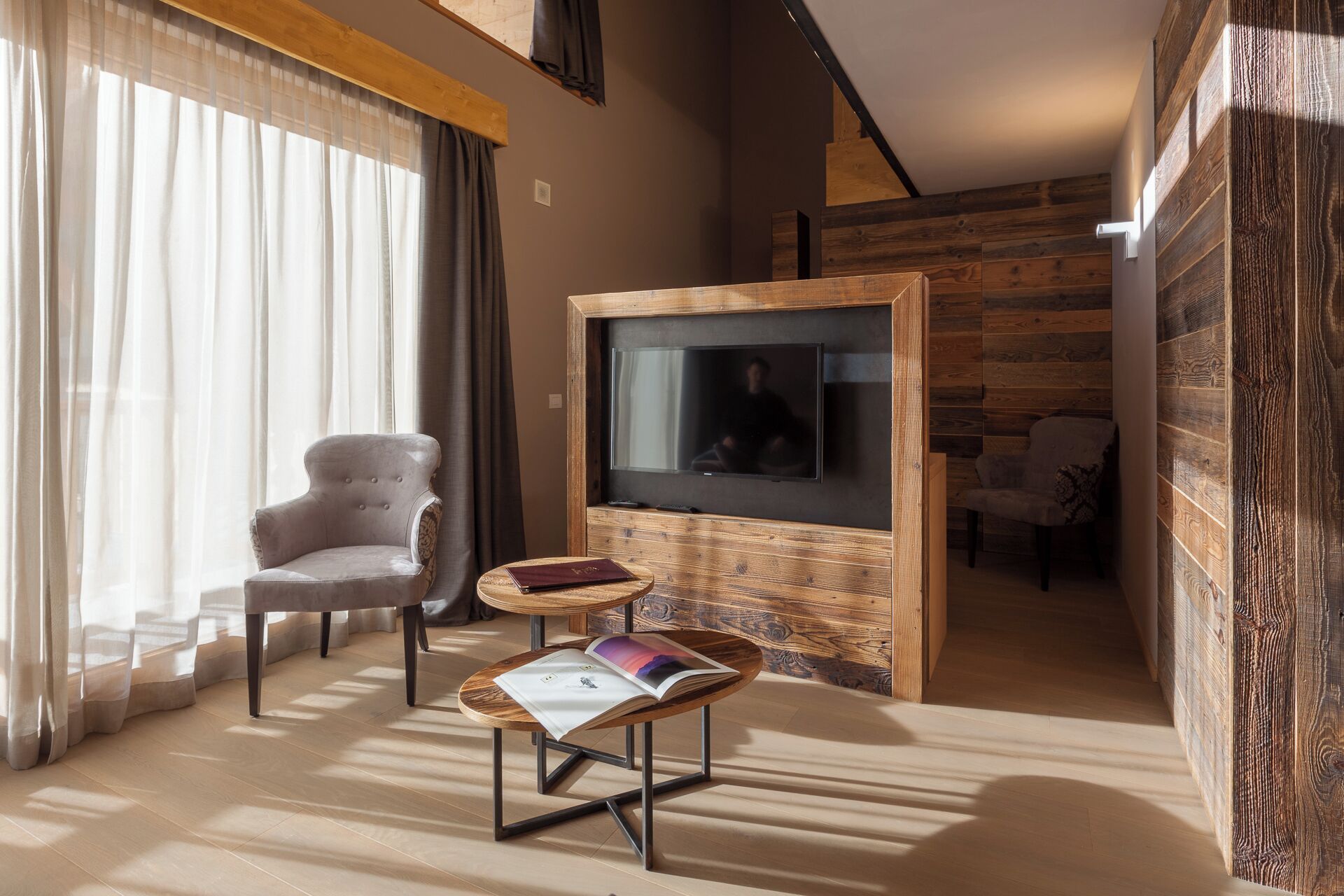 Una sala de estar moderna con un televisor de pantalla plana, un sillón cómodo, una mesita de madera y un sofá.