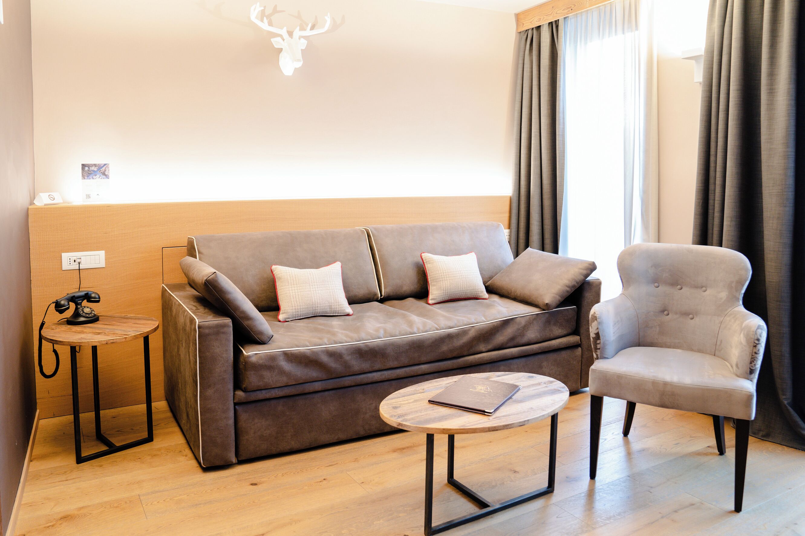 A modern living room with a brown sofa, a round coffee table, and a grey armchair.