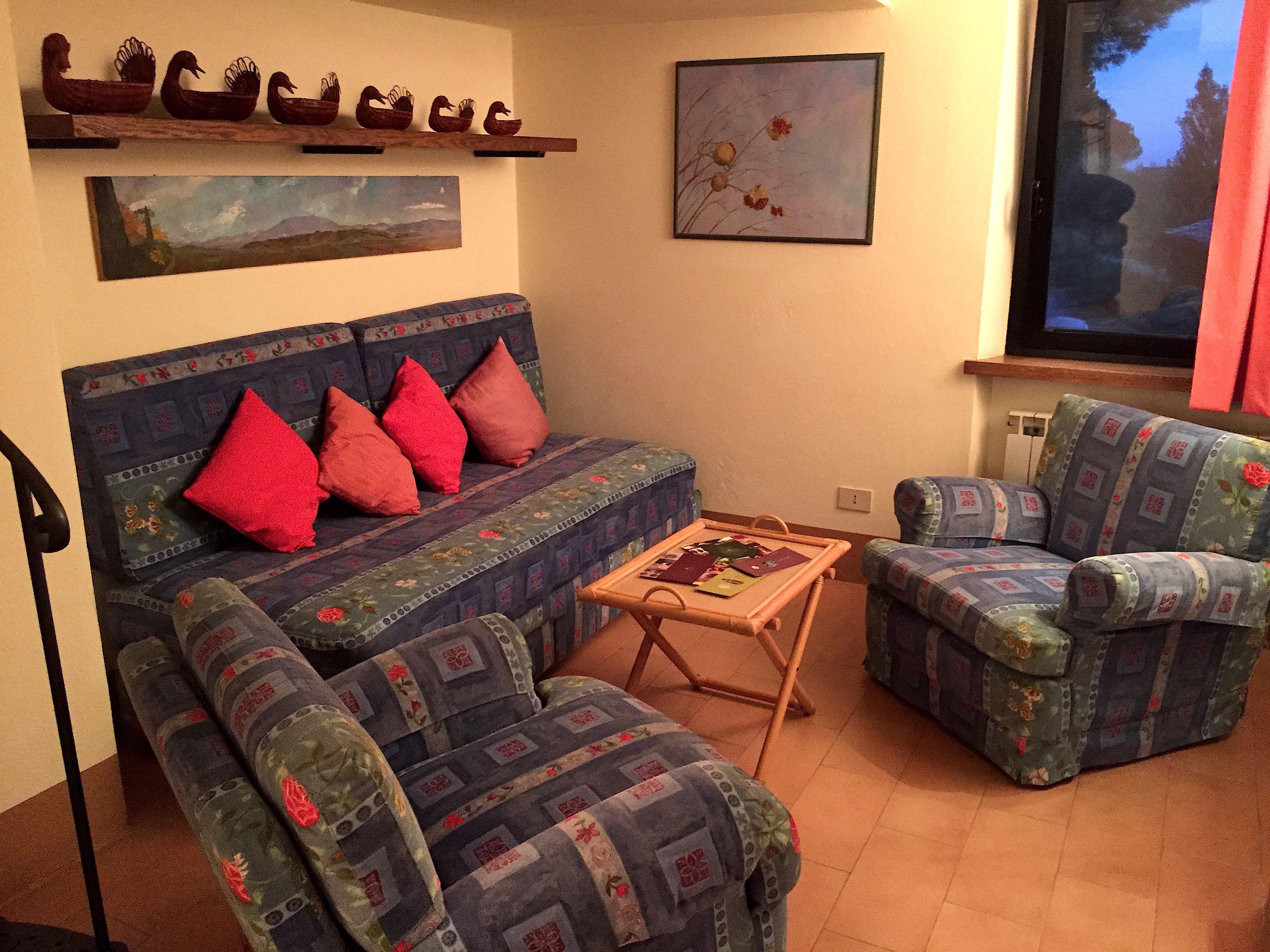 A living room with a sofa, two armchairs, a coffee table, and decorative items on the wall.