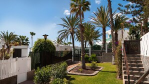 Un cortile con palme, un recinto bianco e una scala che conduce a un edificio.