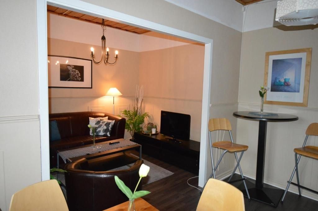 Una sala de estar con sofá, mesa de centro, televisor y un comedor con sillas.