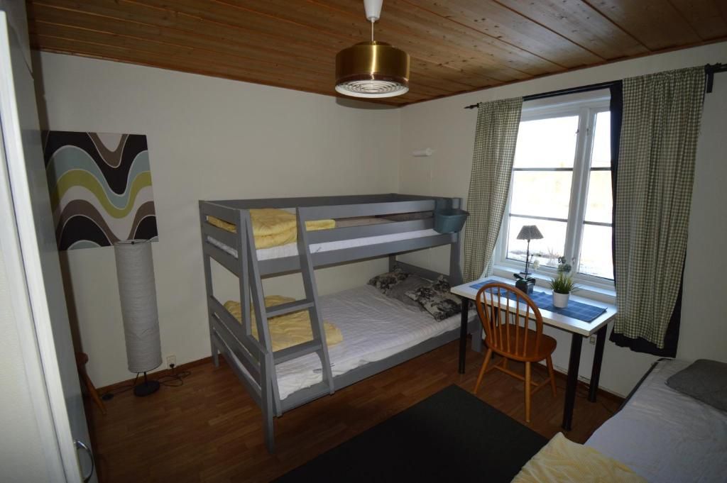 A bunk bed with a desk and chair, a lamp, and a window with curtains.