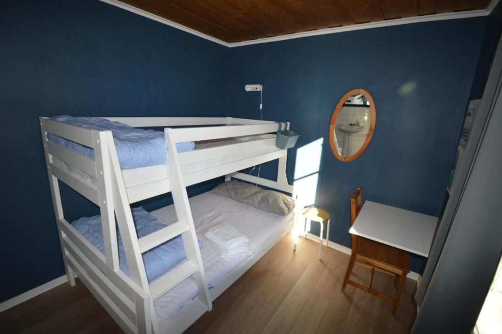 Habitación con literas, escritorio, silla, espejo y ventana.