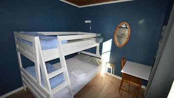 Habitación con literas, escritorio, silla, espejo y ventana.