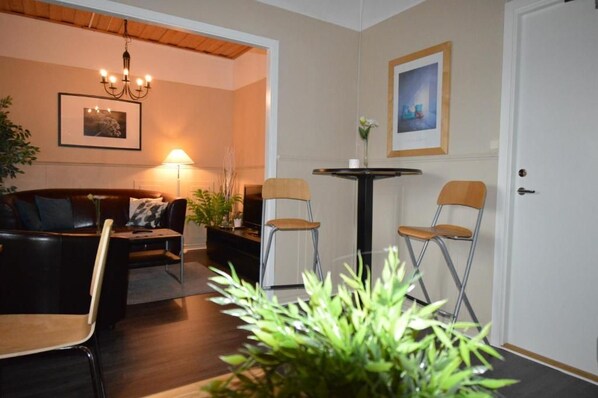 Una habitación acogedora con un sofá, dos sillones, una mesita, una lámpara y un cuadro en la pared.