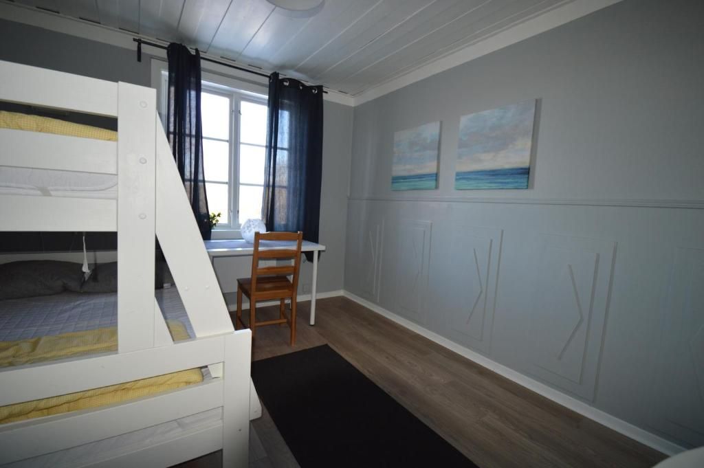 A room with bunk beds, a desk, and a window with curtains.