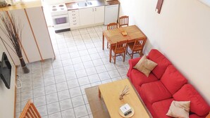 A compact living space with a kitchenette, a dining area, and a red sofa.