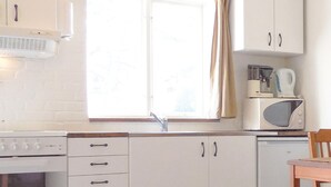 A kitchen with white cabinets, a stove, a microwave, and a coffee maker.