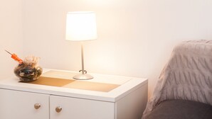 A bedside table with a lamp, a decorative glass vase, and a textured placemat. - Rooms Garden Zagreb Airport (Velika Gorica)