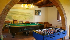 Una habitación con mesa de billar, mesa de fútbol de mesa y un mural en la pared.