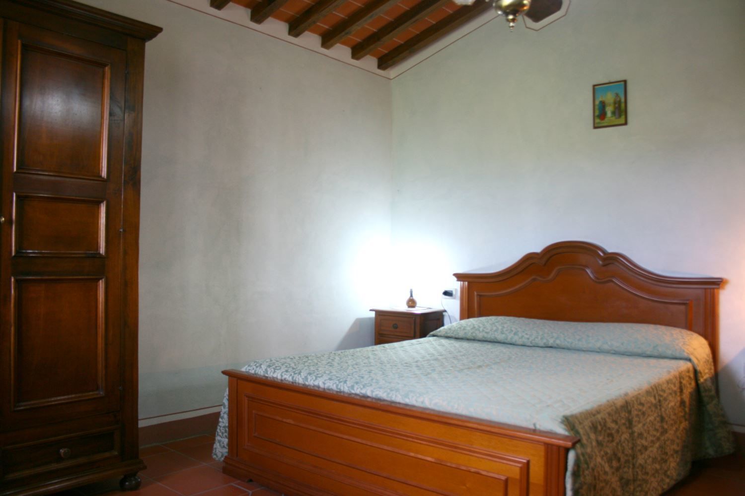 A bedroom with a wooden bed, a nightstand, and a wardrobe.