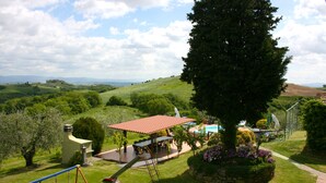 Un patio con un columpio, una zona de estar techada y una piscina.
