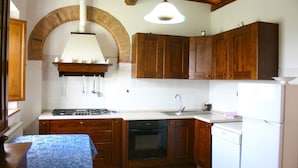 Una cocina con gabinetes de madera, estufa, pileta y lavavajillas.