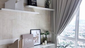 A modern living room with a city view, white shelving, a framed picture, and a small table with bottles. - Gombak126 HomeStay (Kuala Lumpur)