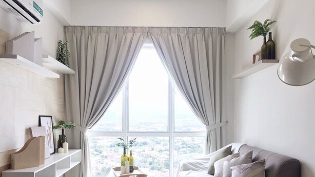 A modern living room with a large window, a grey sofa, and a small table with decorative items. - Gombak126 HomeStay (Kuala Lumpur)
