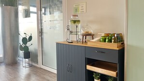 Una cocina moderna con un armario gris, encimera de madera y una puerta de cristal que da a una sala de estar.