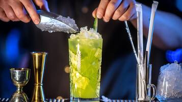 Ein Barkeeper bereitet einen Cocktail mit Eiswürfeln und einer Limettenscheibe zu.