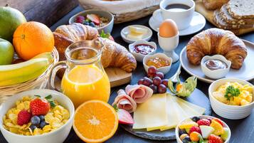 Ein reichhaltiges Frühstücksbuffet mit Croissants, Früchten, Käse und Getränken.