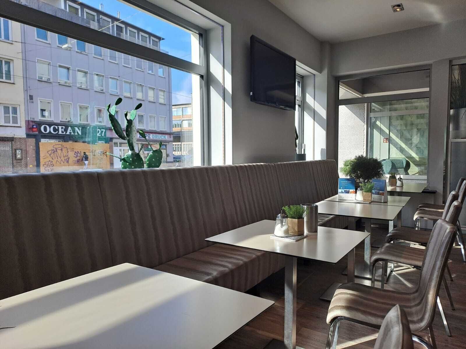 A modern interior with a seating area, tables, and a view of the street outside.