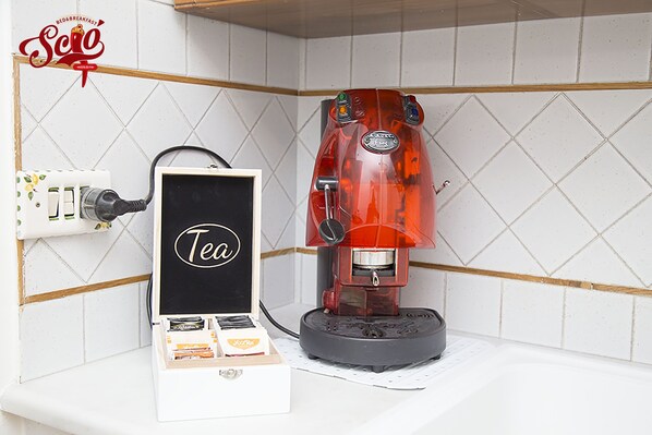 Una cafetera con una caja de té al lado, conectada a un enchufe.