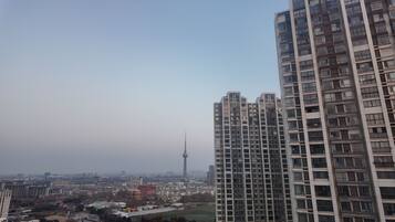 A high-rise building with a view of a cityscape and a tower in the distance.