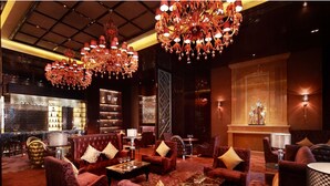 A luxurious lobby with red upholstered seating, chandeliers, and a bar area. - Wanda Realm Taizhou (Taizhou)
