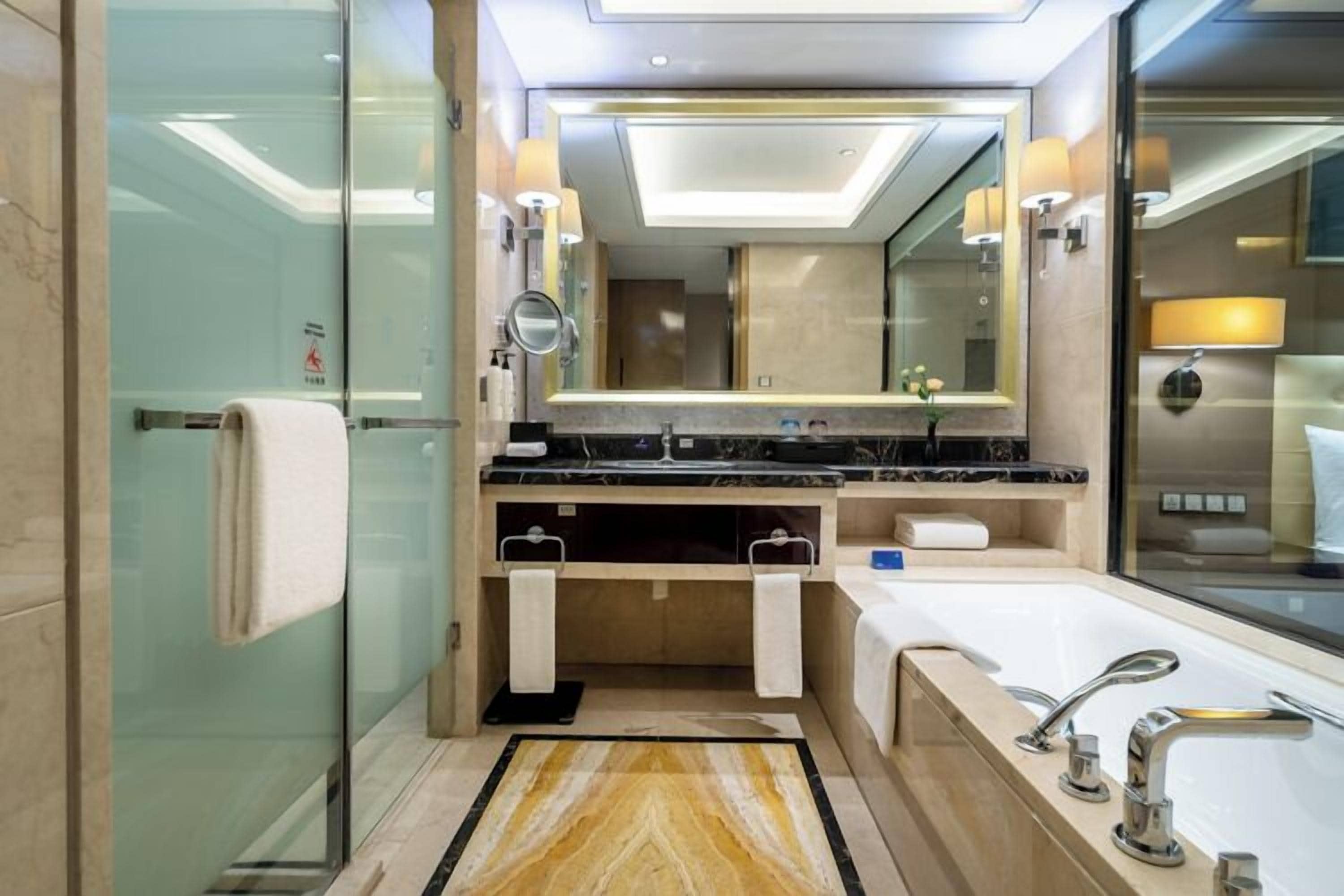 Un baño moderno con cabina de ducha de vidrio, tocador doble y un espejo grande.