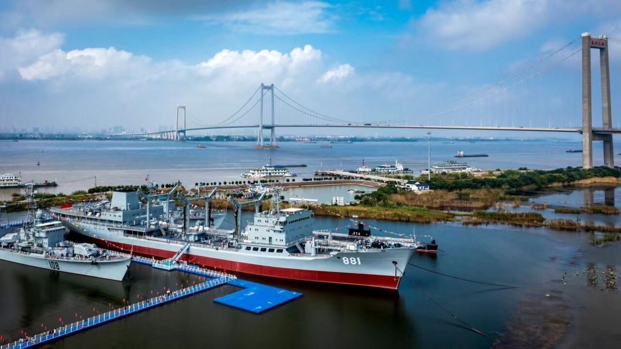 Un barco grande atracado en un puerto, con un puente al fondo.