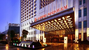 A modern hotel entrance with a covered entrance area and a large sign reading "Wanda Realm". - Wanda Realm Taizhou (Taizhou)