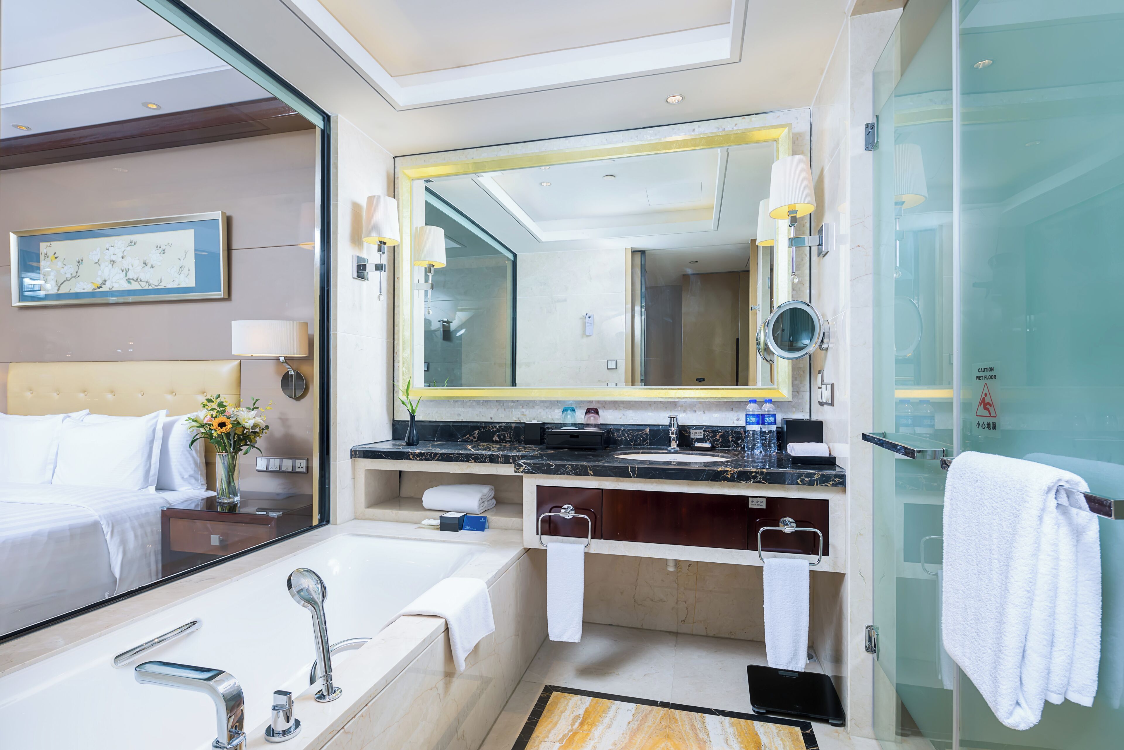 Un baño de hotel moderno con un espejo grande, una bañera, una ducha y un tocador con lavabo.
