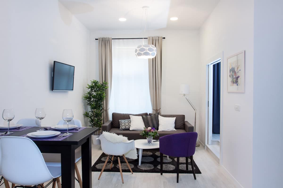 Un salon moderne comprenant un coin repas, un canapé, une table basse et un téléviseur fixé au mur.