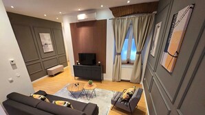 Een moderne woonkamer met een bank, een salontafel, een televisie en een raam met gordijnen.