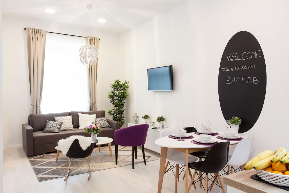 Un salon moderne avec un canapé, une table à manger, des chaises et un panier de fruits.