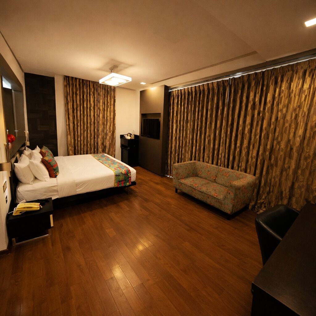 Une chambre d’hôtel avec un lit, un canapé, un bureau et une télévision.